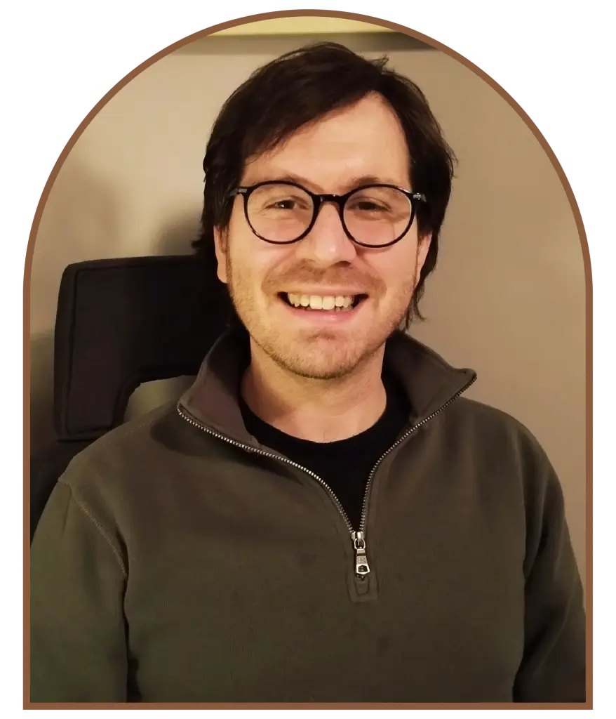 Smiling man wearing glasses and olive green fleece jacket.