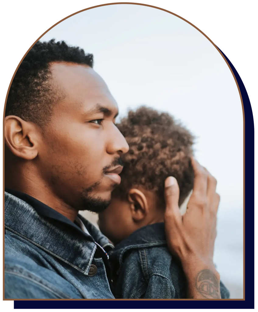 Father holding young son outdoors, side profile view.