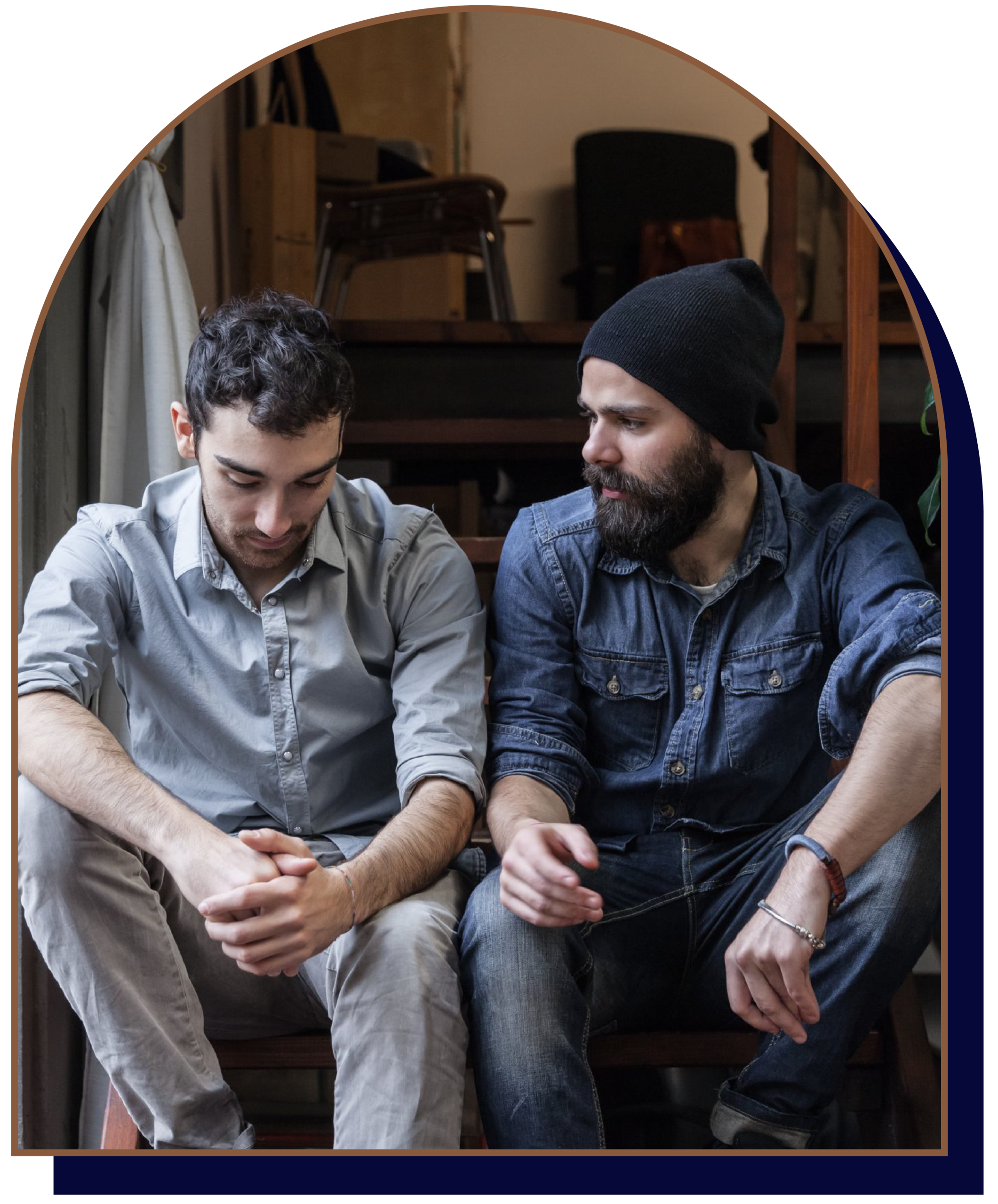 Men's counselling Waterloo Region - Two men sitting on stairs having a conversation indoors.