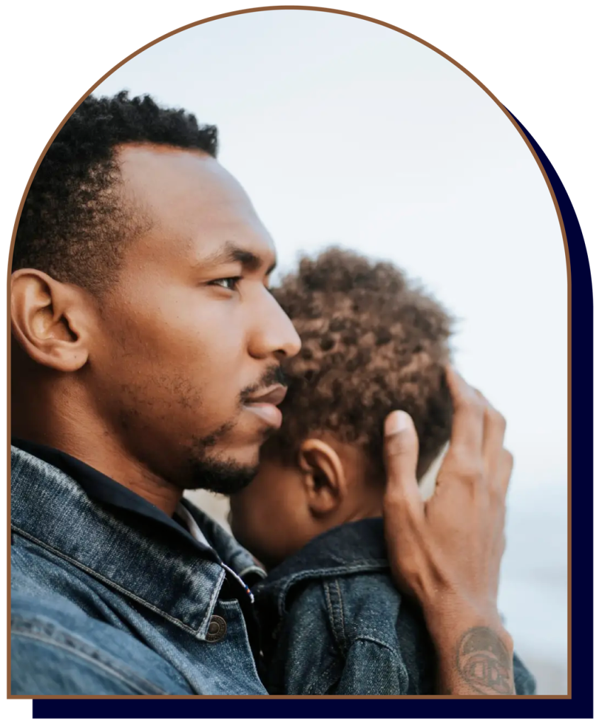 Father holding young son outdoors, side profile view.