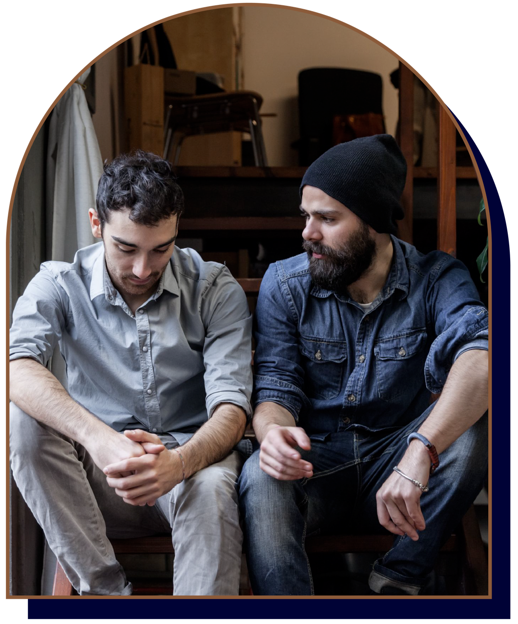 Men's counselling Waterloo Region - Two men sitting on stairs having a conversation indoors.