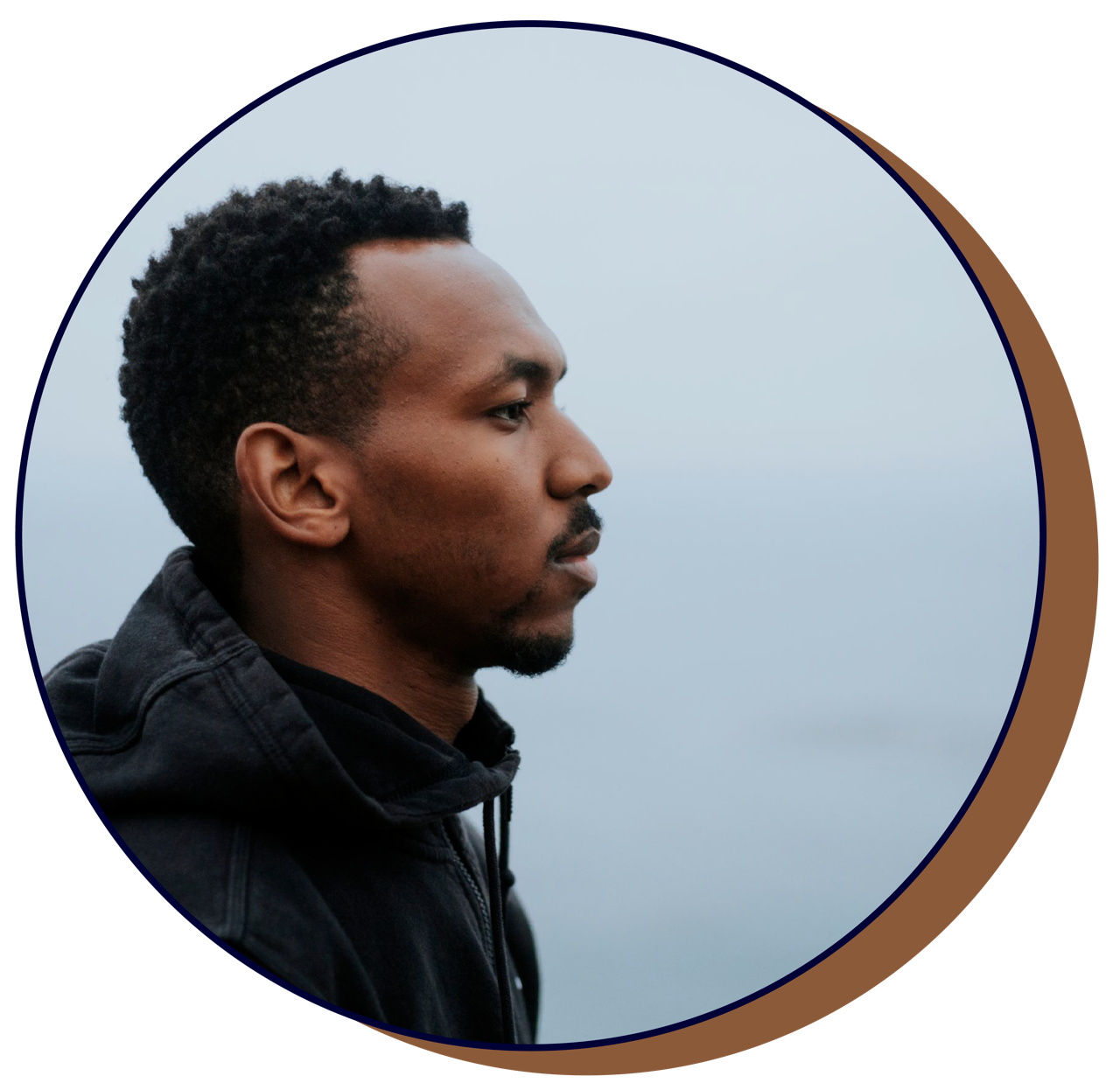 Profile portrait of man in black jacket against blue sky.